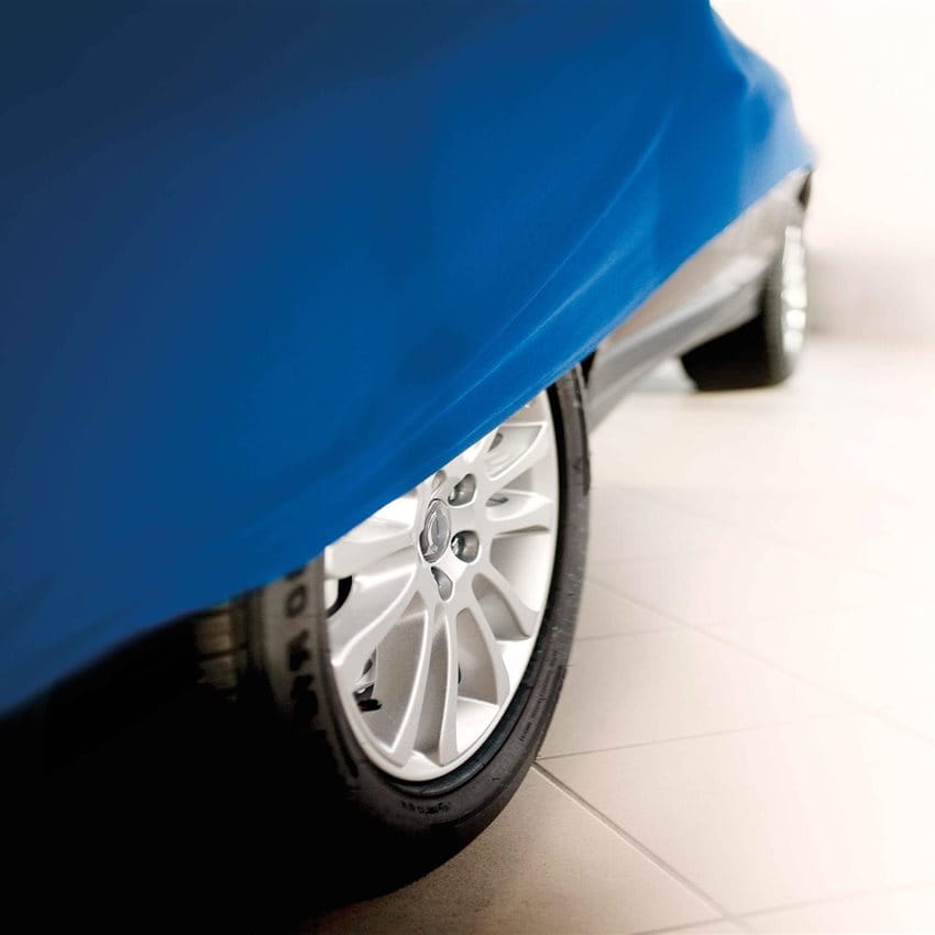 A car covered with a blue cloth, only the wheel and floor are visible. A car covered with a blue cloth, only the wheel and floor are visible.