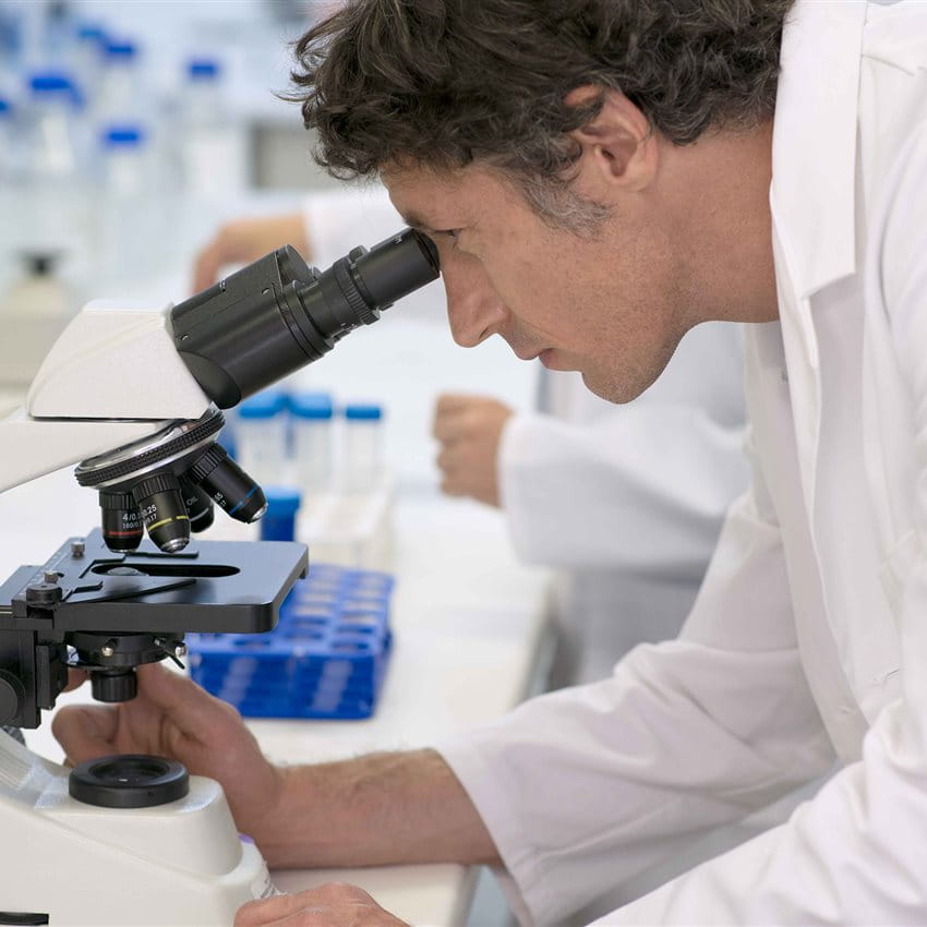 Un uomo osserva attraverso un microscopio in un laboratorio. Un uomo osserva attraverso un microscopio in un laboratorio.