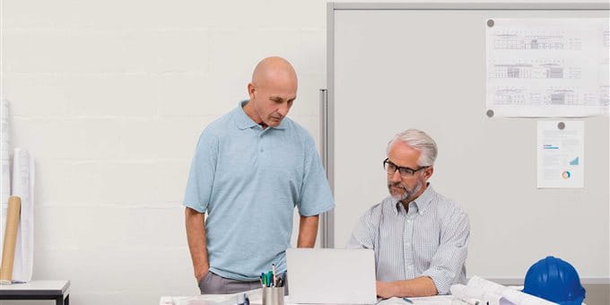 An employee explains something to a colleague at the laptop in an office. An employee explains something to a colleague at the laptop in an office.
