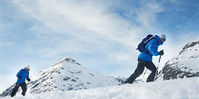 Zwei Personen im Schnee, die einen Berg hochsteigen, umgeben von schneebedeckten Hügeln und strahlend blauem Himmel. Zwei Personen im Schnee, die einen Berg hochsteigen, umgeben von schneebedeckten Hügeln und strahlend blauem Himmel.