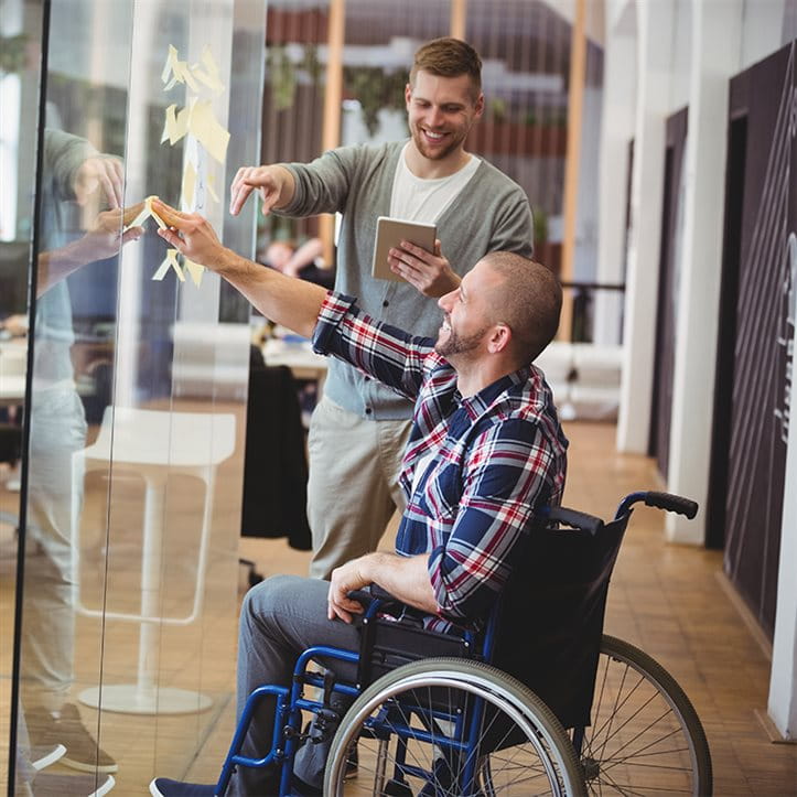 Two men in a modern office with sticky notes on a glass wall. Two men in a modern office with sticky notes on a glass wall.