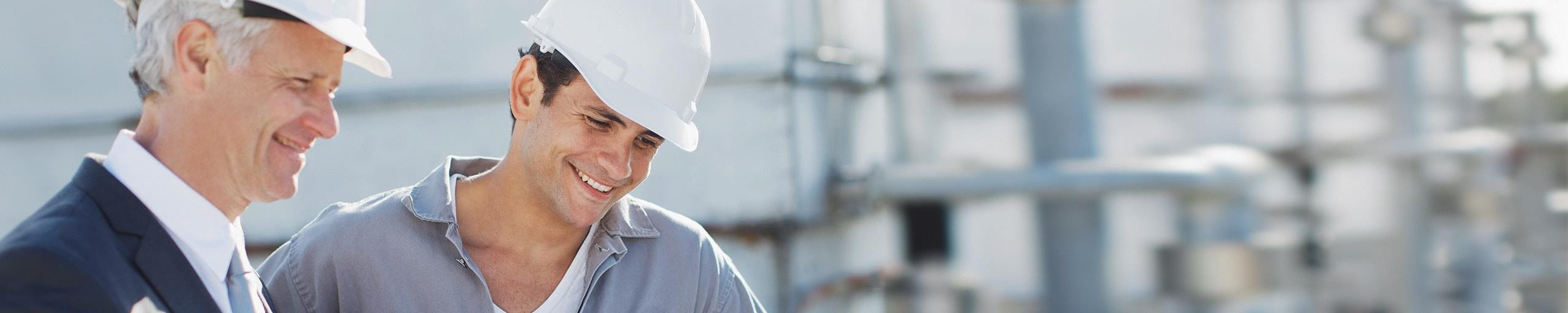 Deux hommes avec des casques de protection discutent sur un chantier.
