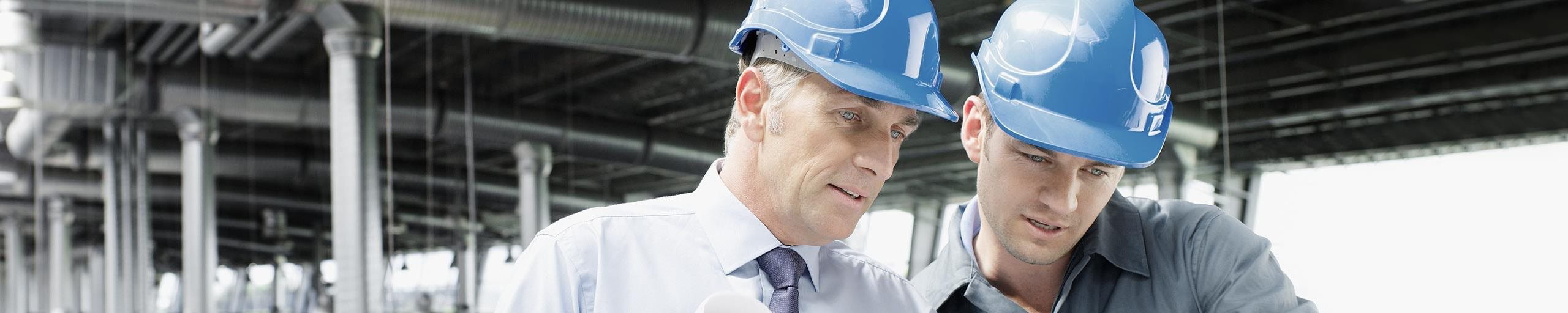 Deux hommes avec des casques de protection discutent sur un chantier.