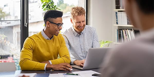 Deux hommes travaillent sur un ordinateur portable