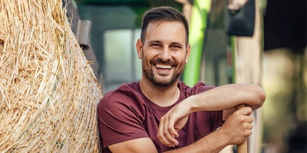 Agriculteur s'appuyant sur une balle de foin