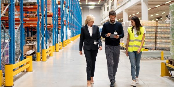 Deux femmes et un homme traversent un entrepôt