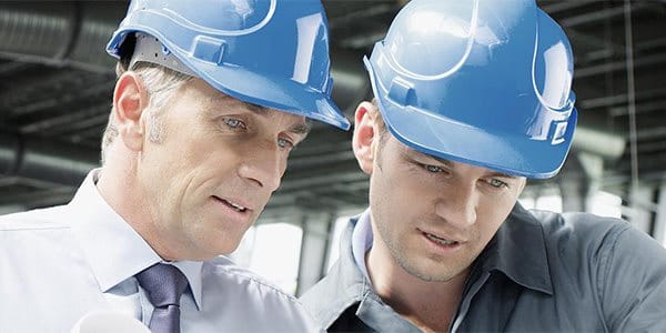 Deux hommes avec des casques de protection discutent sur un chantier.