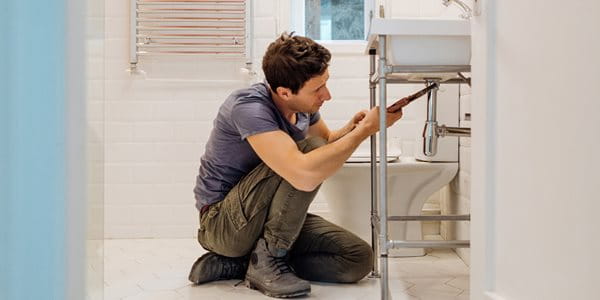 Artisan plombier dans la salle de bain en train de réparer le siphon