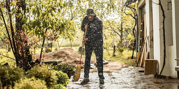 Un homme nettoie une terrasse mouillée après une pluie persistante