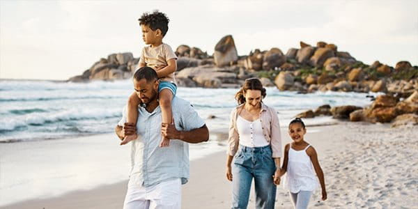 Un couple de famille marche sur une plage de sable avec 2 enfants