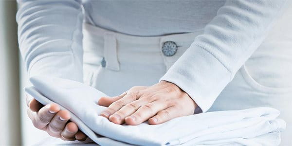 Une personne plie un linge sur une planche à repasser.