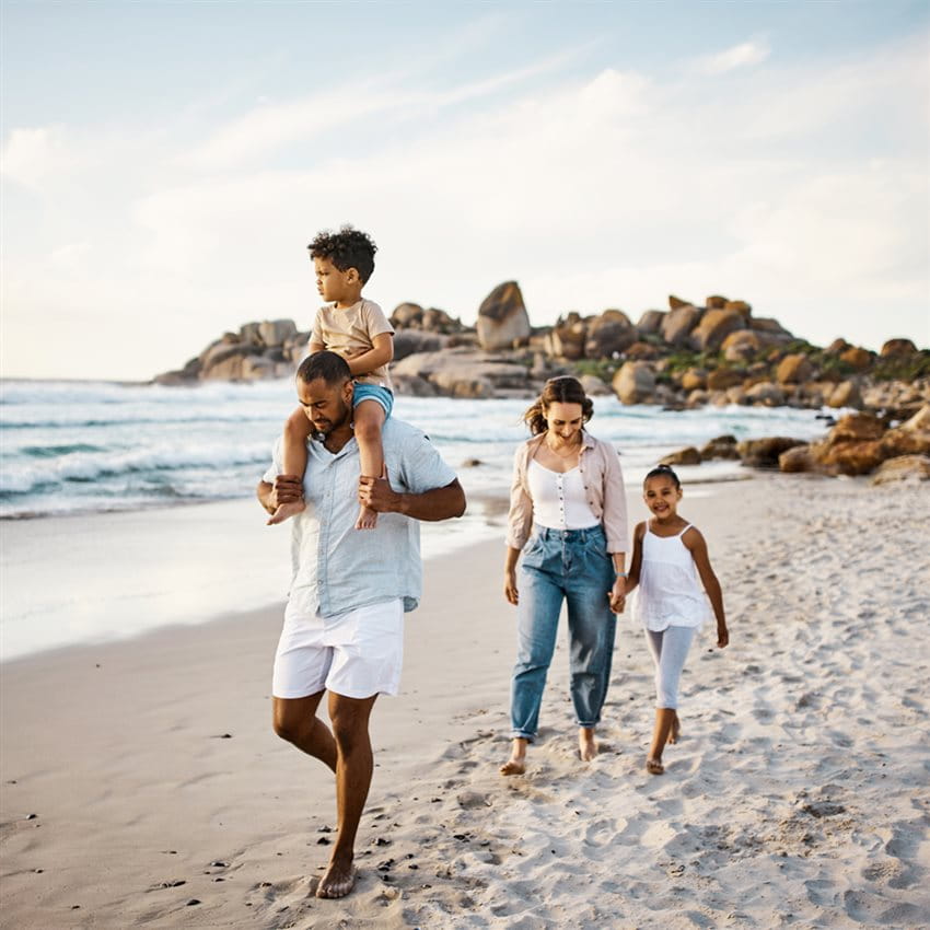 Un couple de famille marche sur une plage de sable avec 2 enfants Un couple de famille marche sur une plage de sable avec 2 enfants