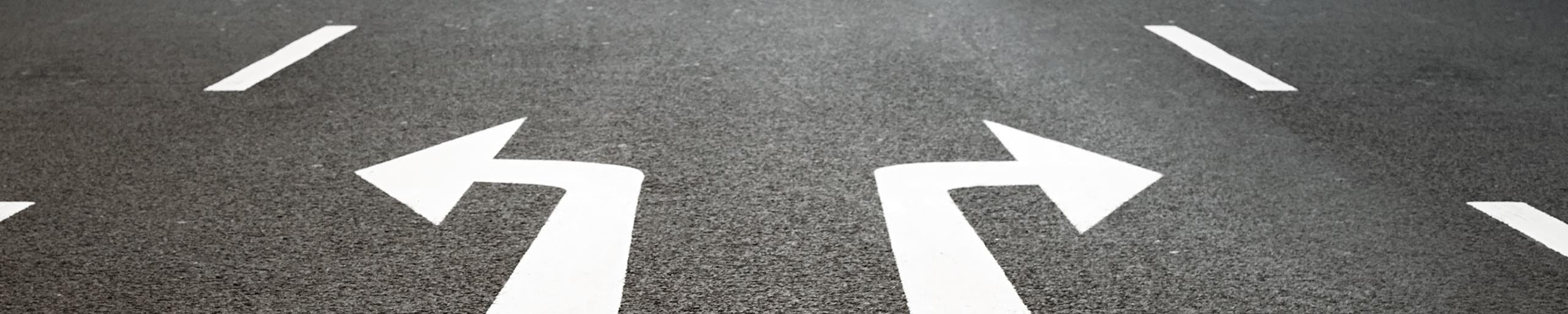 Zwei Richtungspfeile auf einer Strasse.