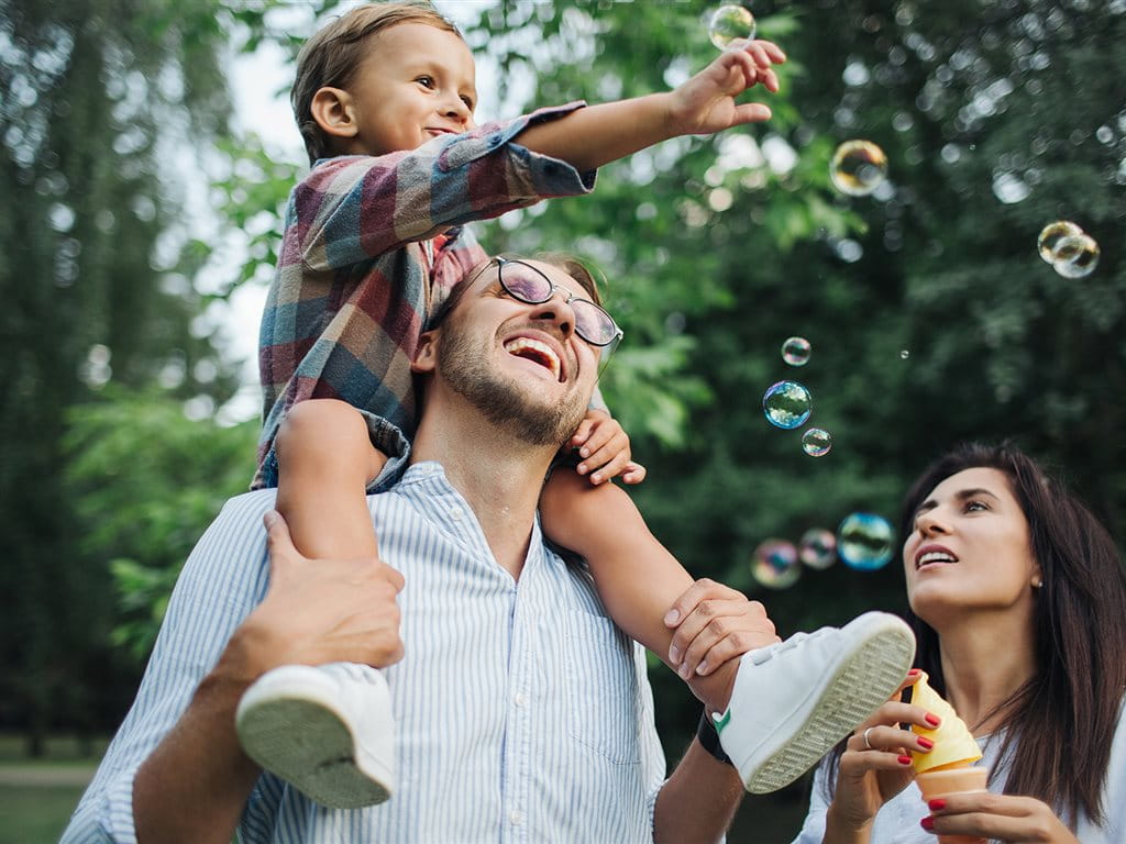 Una famiglia gioca insieme all’aperto, facendo bolle di sapone.