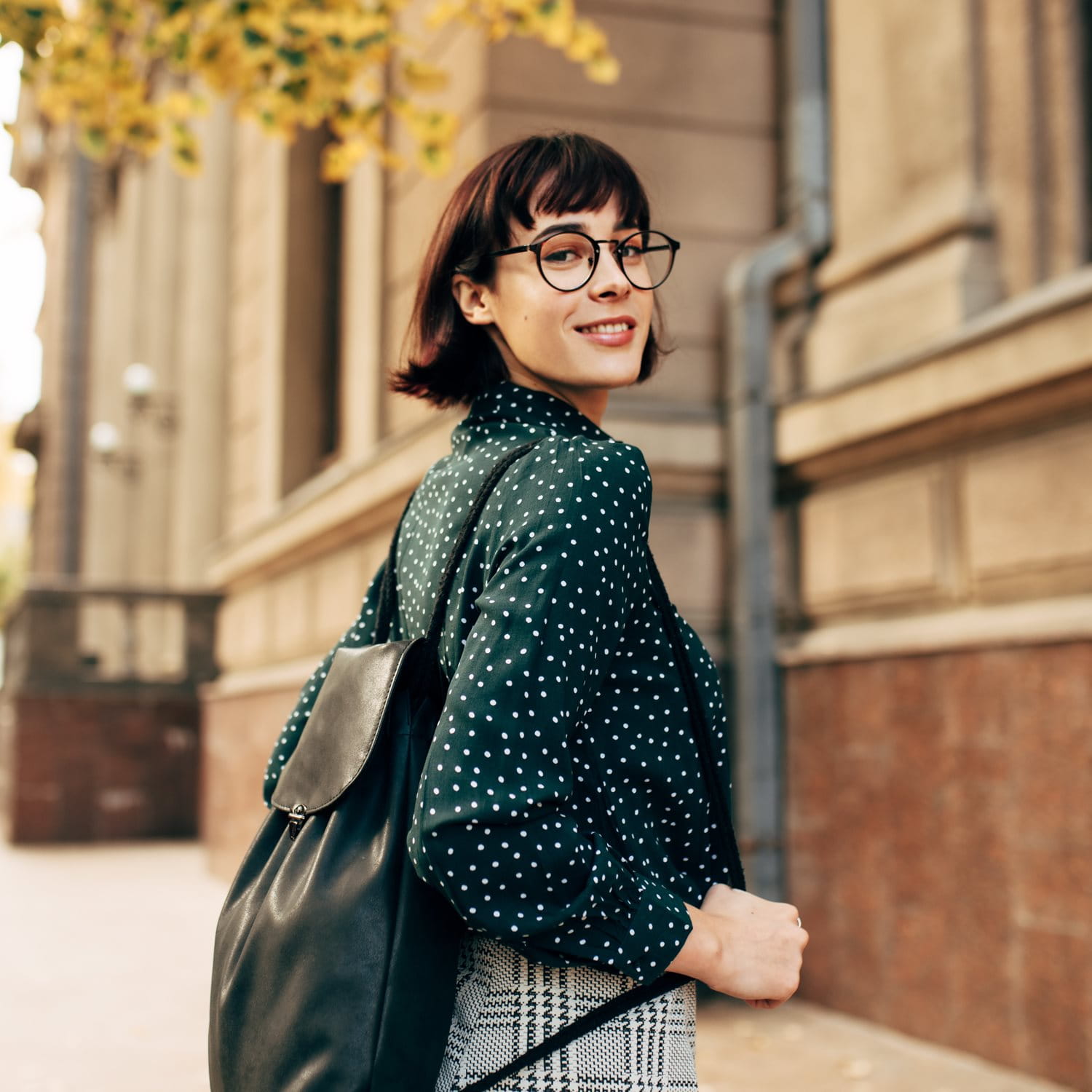 Frau mit Rucksack vor historischem Gebäude.