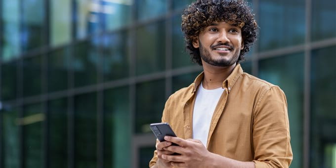 Personne debout devant un bâtiment moderne, tenant un smartphone. Personne debout devant un bâtiment moderne, tenant un smartphone.