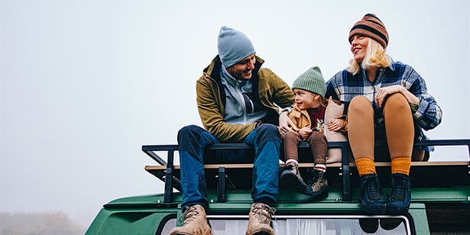 An adult and a child sit together at a breakfast table in a bright kitchen. In front of them are bowls of cereal, glasses of orange juice, mugs, a plate of bread slices, and a bowl of fresh fruit. Both have their arms raised and appear to be interacting in a joyful manner. An adult and a child sit together at a breakfast table in a bright kitchen. In front of them are bowls of cereal, glasses of orange juice, mugs, a plate of bread slices, and a bowl of fresh fruit. Both have their arms raised and appear to be interacting in a joyful manner.