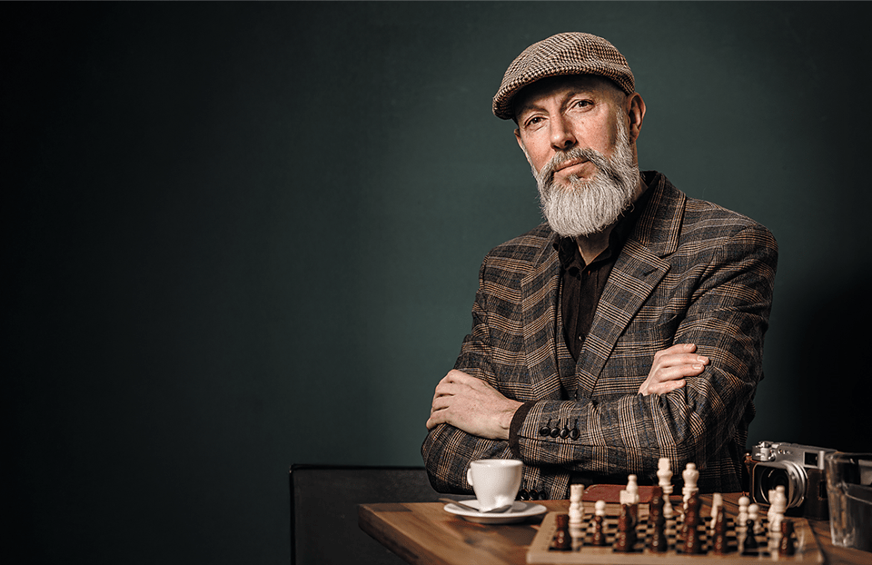 Gut gekleideter, älterer Mann mit Schachbrett Gut gekleideter, älterer Mann mit Schachbrett