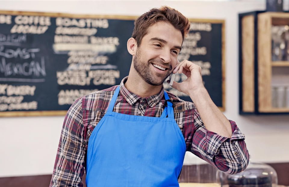 Mann in blauer Schürze telefoniert Mann in blauer Schürze telefoniert