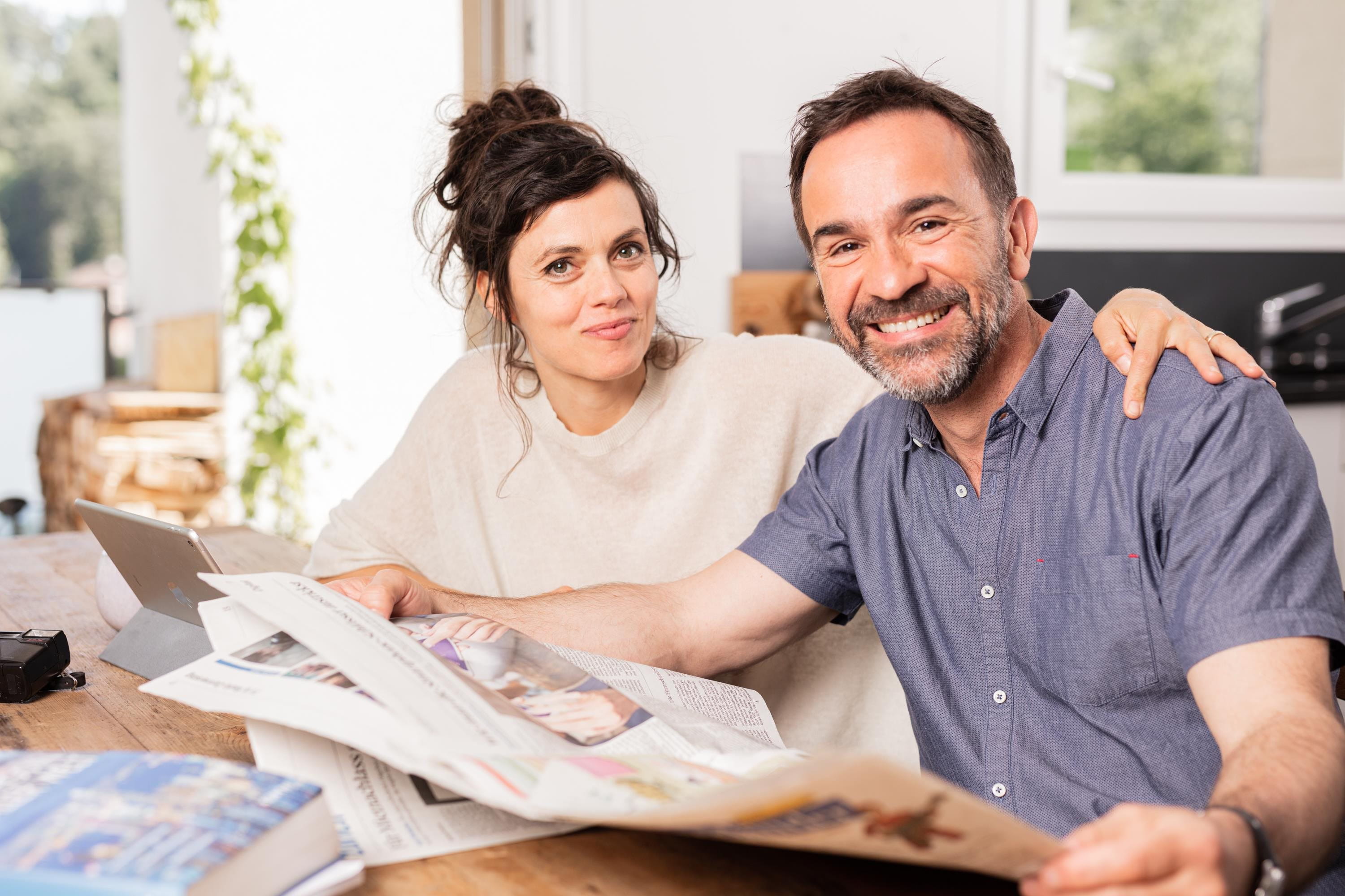 Woman and man reading newspaper at table