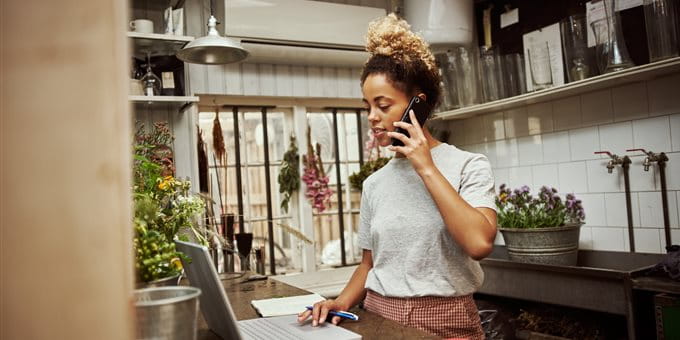 Femme travaille dans un magasin de fleurs sur ordinateur et téléphone. Femme travaille dans un magasin de fleurs sur ordinateur et téléphone.