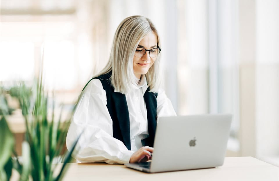 A professional working on a laptop in a bright, modern office space. A professional working on a laptop in a bright, modern office space.