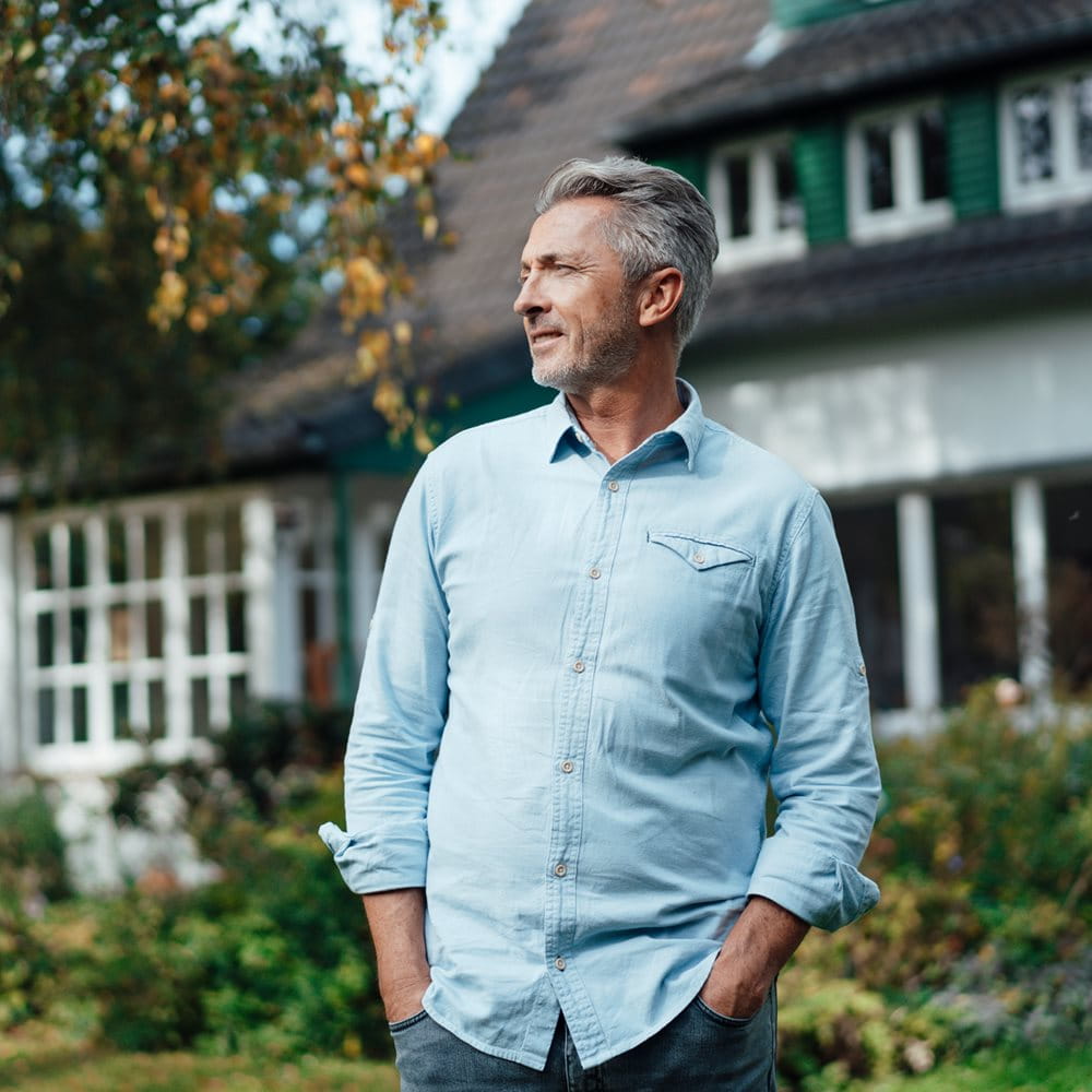 Mann im Garten seines Hauses