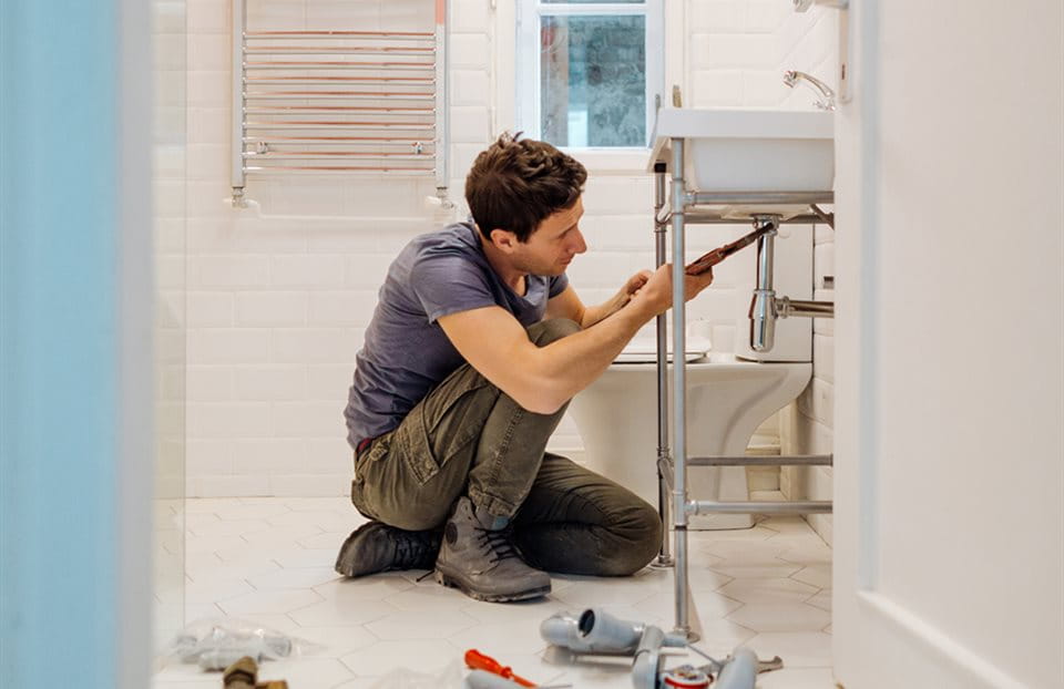Un idraulico artigiano in bagno che ripara lo scarico Un idraulico artigiano in bagno che ripara lo scarico