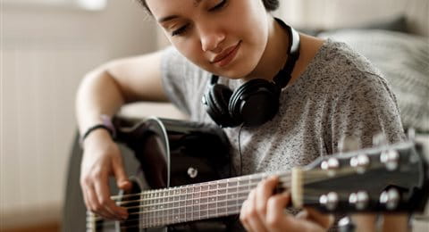 Jugendlicher spielt auf seiner wertvollen Gitarre Jugendlicher spielt auf seiner wertvollen Gitarre