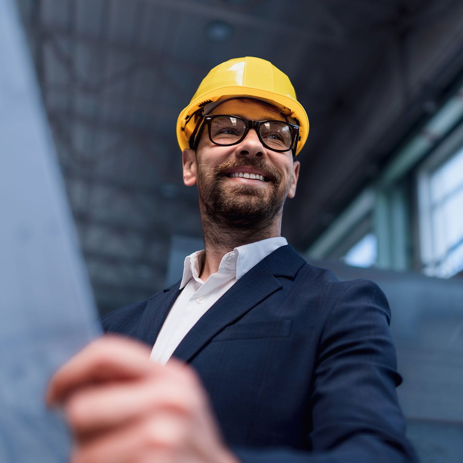 Man with yellow helmet and blueprint on construction site