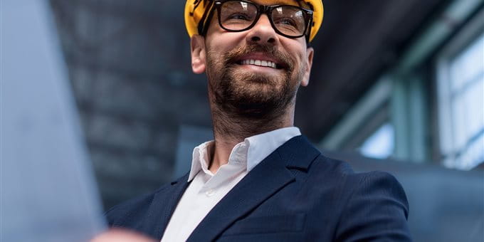 Uomo con casco giallo e progetto in cantiere Uomo con casco giallo e progetto in cantiere