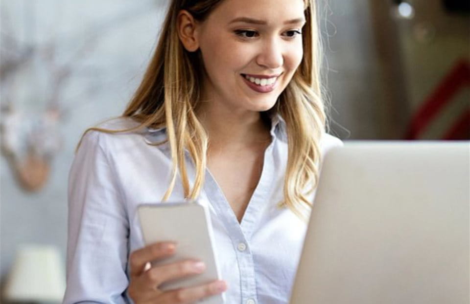 Frau mit Handy am Laptop Frau mit Handy am Laptop