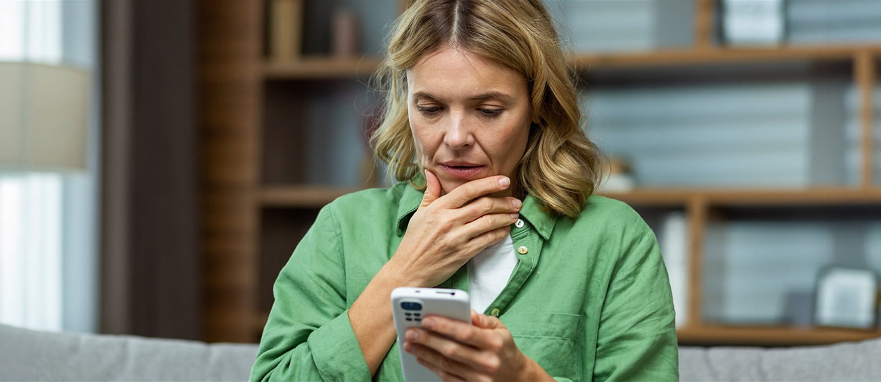 Woman looks anxiously at her smartphone Woman looks anxiously at her smartphone