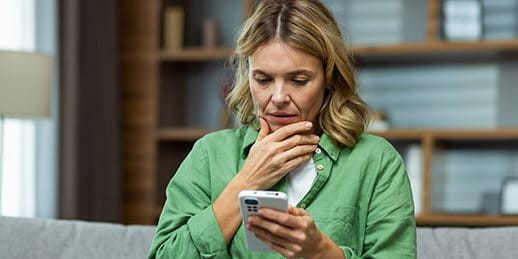 Frau schaut besorgt auf ihr Smartphone