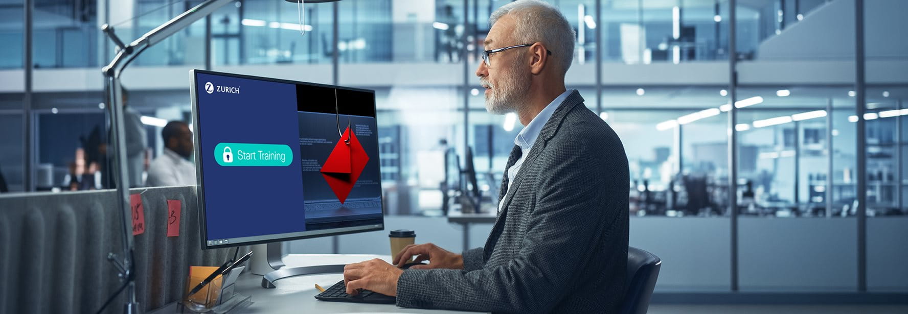 Mann vor Computer mit Zurich Cyber-Training und Phishing-Warnung im Büro.