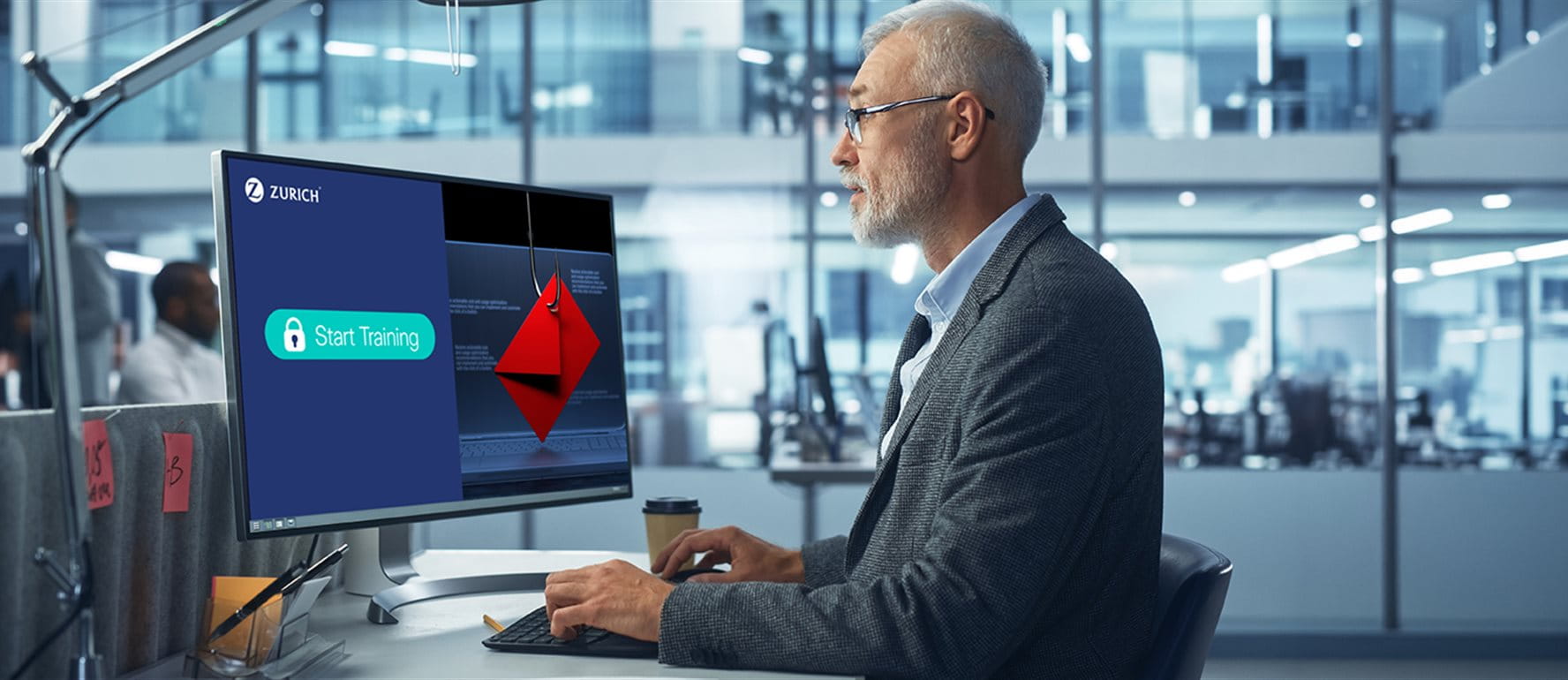 Mann vor Computer mit Zurich Cyber-Training und Phishing-Warnung im Büro. Mann vor Computer mit Zurich Cyber-Training und Phishing-Warnung im Büro.