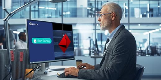 Mann vor Computer mit Zurich Cyber-Training und Phishing-Warnung im Büro.