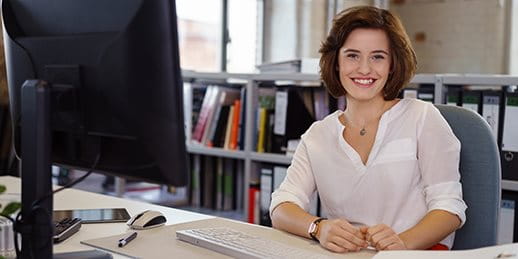 A person is sitting at a desk in front of a computer. A person is sitting at a desk in front of a computer.