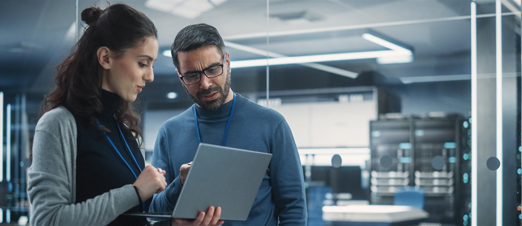 A woman and a man look into a laptop together A woman and a man look into a laptop together