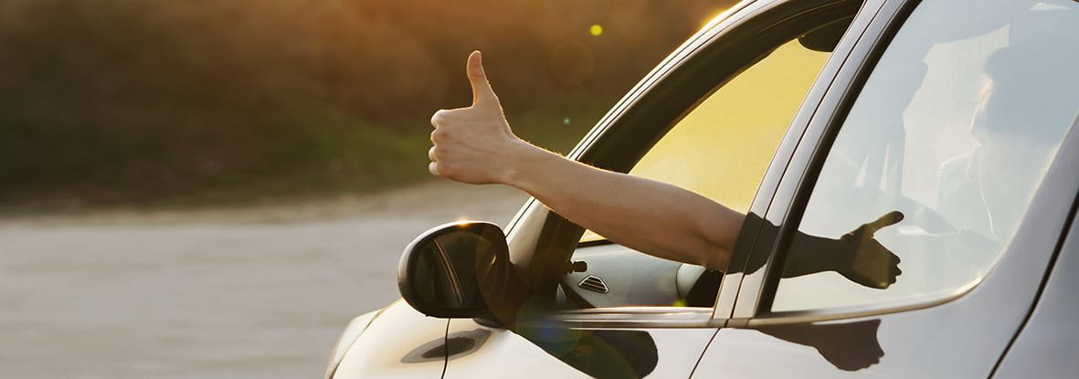 Eine Hand mit Daumen nach oben zeigt aus einem Autofenster. Eine Hand mit Daumen nach oben zeigt aus einem Autofenster.