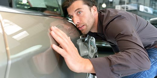 Un homme examine attentivement la peinture d'une voiture