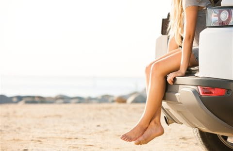 Junge Frau sitzt im Kofferraum eines Autos  Junge Frau sitzt im Kofferraum eines Autos