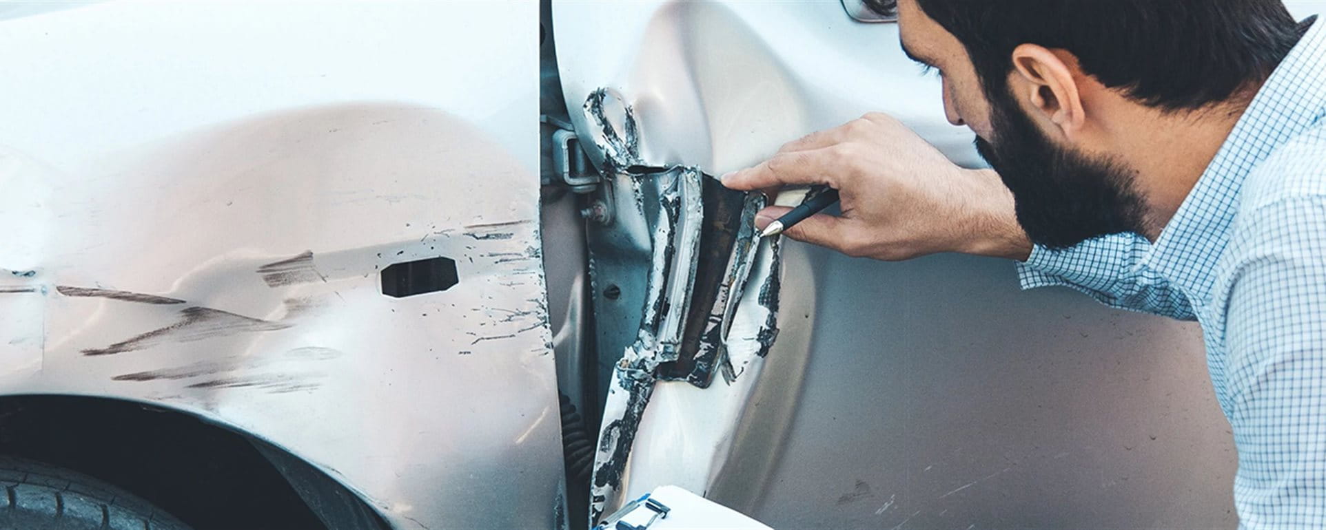 L’uomo esamina i danni al veicolo  L’uomo esamina i danni al veicolo