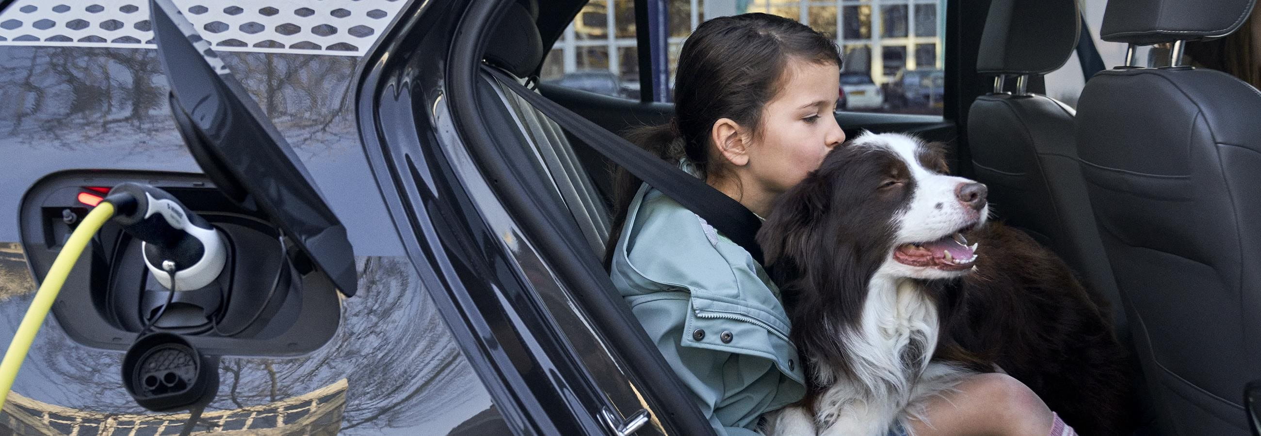 Maedchen kuschelt einen Hund im Auto
