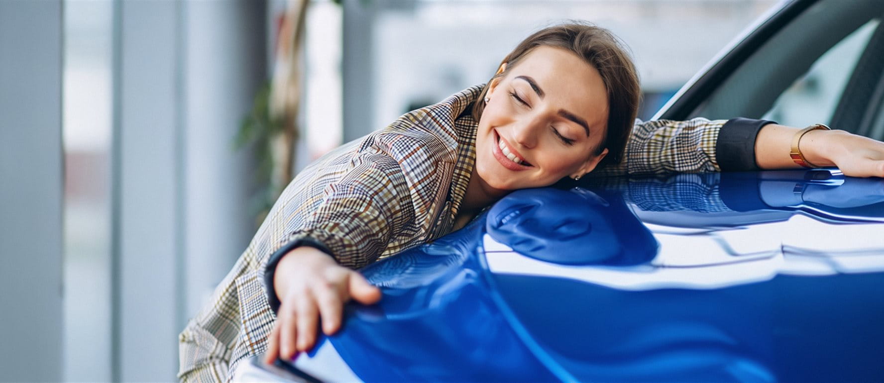 Une femme étreint joyeusement une voiture bleue. Elle sourit et semble satisfaite. Une femme étreint joyeusement une voiture bleue. Elle sourit et semble satisfaite.