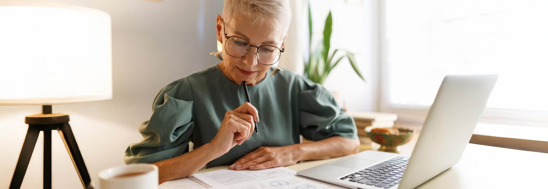 Femme assise devant un ordinateur portable avec un stylo et du papier