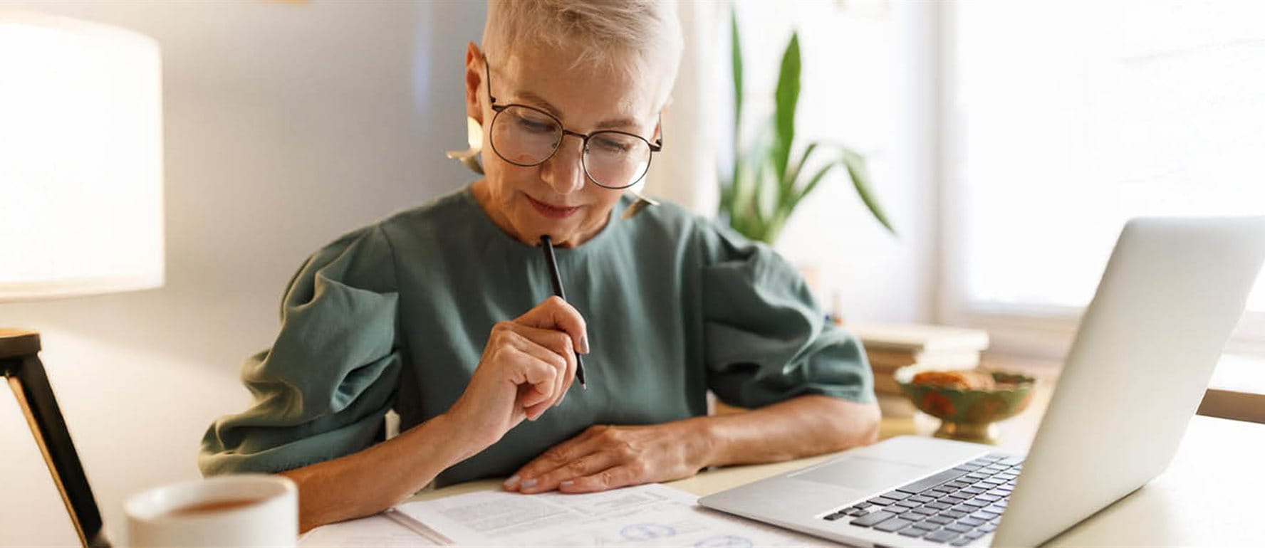 Donna seduta davanti a un computer portatile con carta e penna Donna seduta davanti a un computer portatile con carta e penna