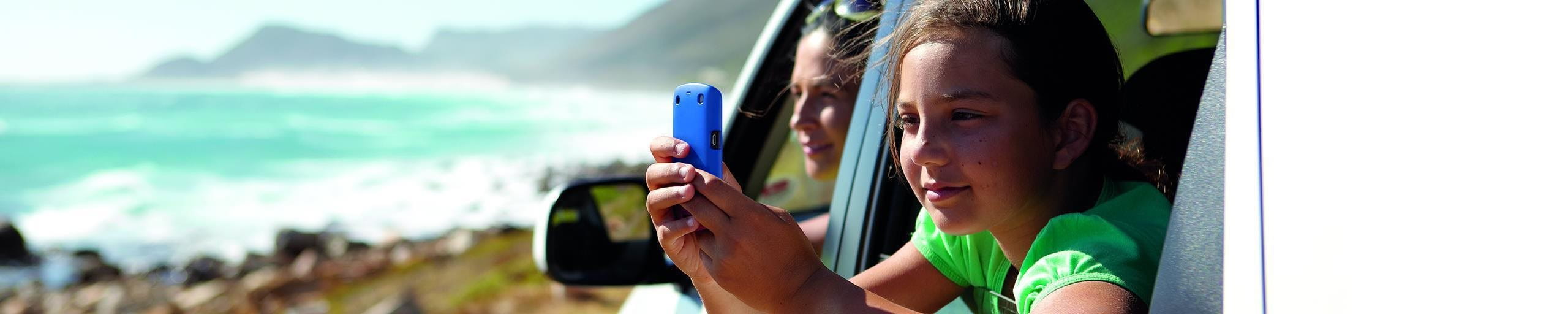 Kind mit Handy im Auto