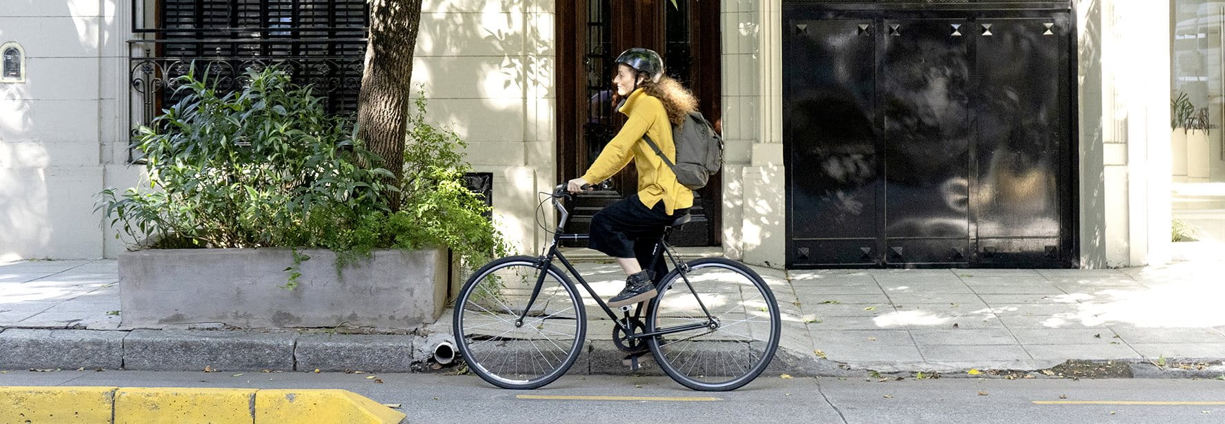 Eine Person fährt auf einem Fahrrad auf einem Gehweg mit Pflanzenbeeten.