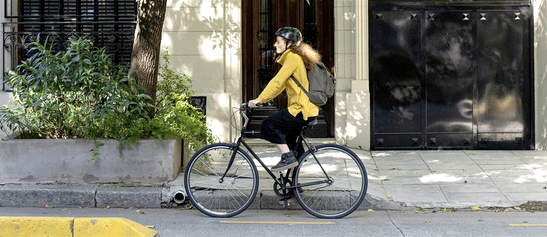 Eine Person fährt auf einem Fahrrad auf einem Gehweg mit Pflanzenbeeten. Eine Person fährt auf einem Fahrrad auf einem Gehweg mit Pflanzenbeeten.